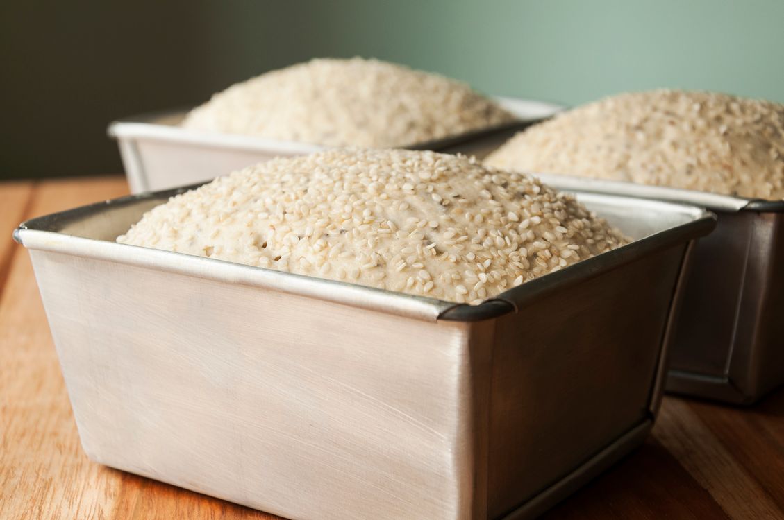 Massa de pão crescida em formas retangulares de metal, prontas para assar